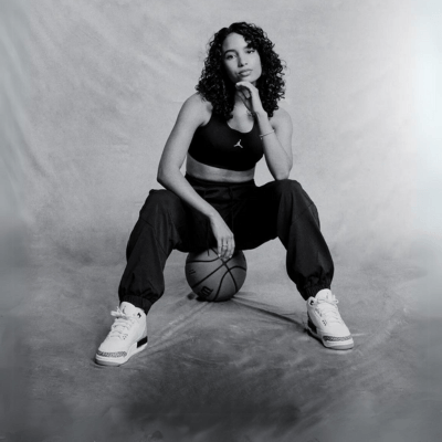 Woman sitting on a basketball ball posing with Air Jordan 3 sneakers