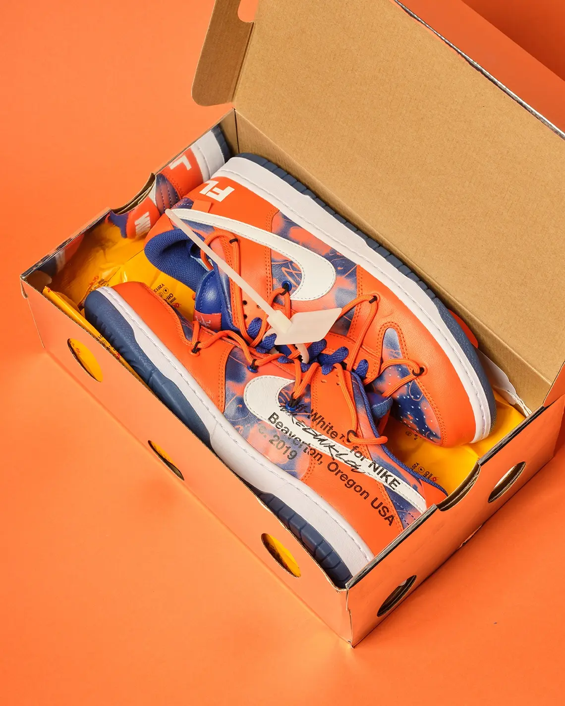 The Futura x Off-White x Nike Dunk 'Syracuse' met oranje achtergrond